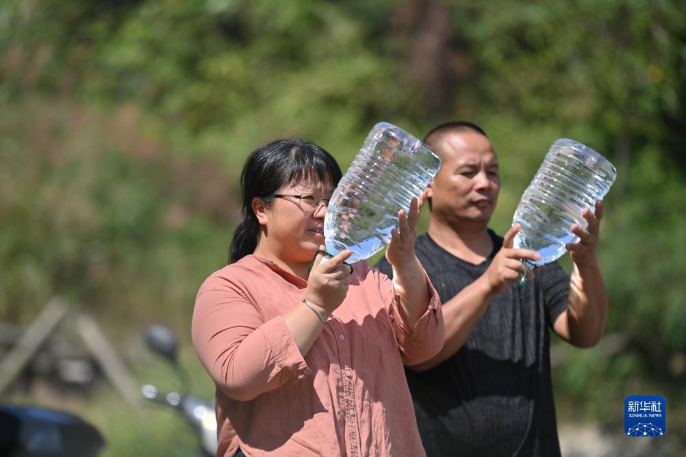 楊寧（左）在查看村民剛剛采集的水樣，為山泉水引水工程做準(zhǔn)備（10月8日攝）。新華社記者 黃孝邦 攝